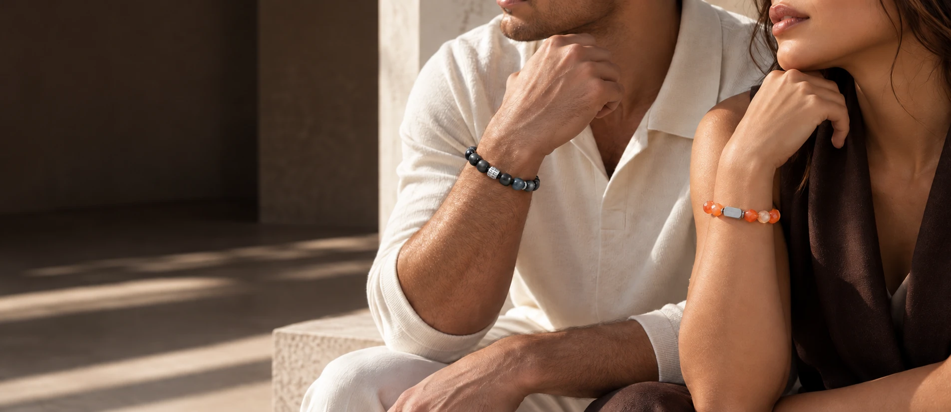 Two adults wearing dark stone and orange agate bracelets in natural light
